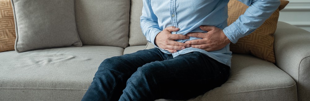 Mann hält sich den Bauch; Foto: Grustock/Shutterstock.com