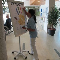 Eine Mitarbeiterin der Kanzlei des Rehabilitationszentrums unterschreibt auf dem Plakat -Wir machen mit!- und zeigt damit ihre der Unterstützung des Programms.