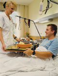 Patient im Krankenbett erhält Essen,  AUVA-Archiv