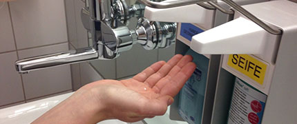 Nahaufnahme einer Hand am Desinfektionsmittelspender 