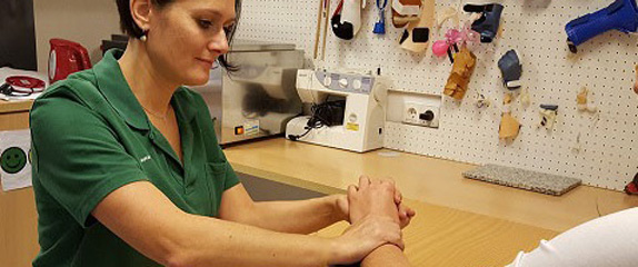 Ergotherapeutin arbeitet an der Hand einer Patientin.