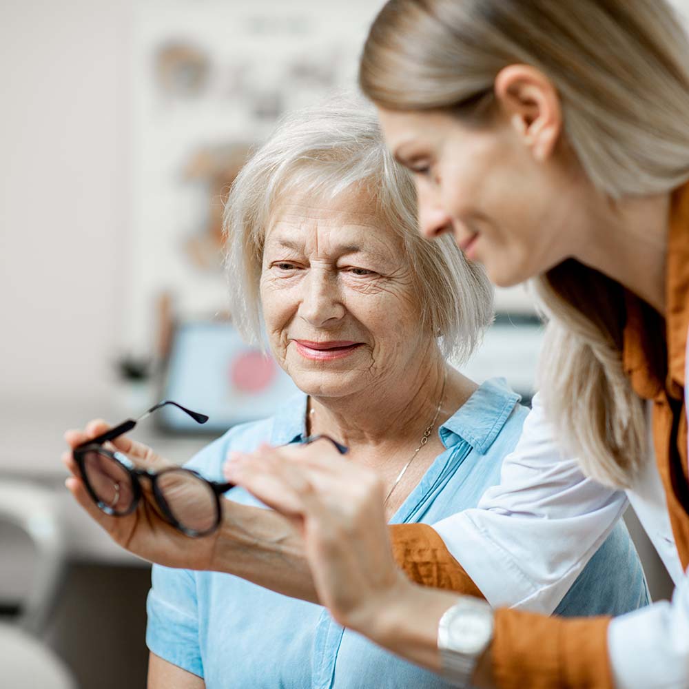 Ärztin reicht älterer Frau eine Brille. / Credit: Ross Helen/shutterstock.com